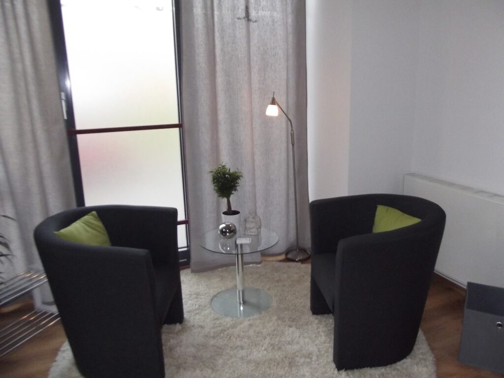 Das Foto zeigt einen Praxisraum in dem zwei Sessel gegenübergestellt sind und zum Gespräch einladen.