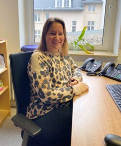 Das Bild zeigt unsere Leitung des AGBT Bereichs Eleni Krautz. Sie sitzt hier am Schreibtisch im Büro.